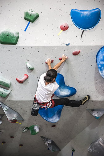 Man Climbing Indoor Rock Wall with Chalk Bag