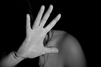 Black and white close-up of a woman's open hand raised in a defensive stop gesture