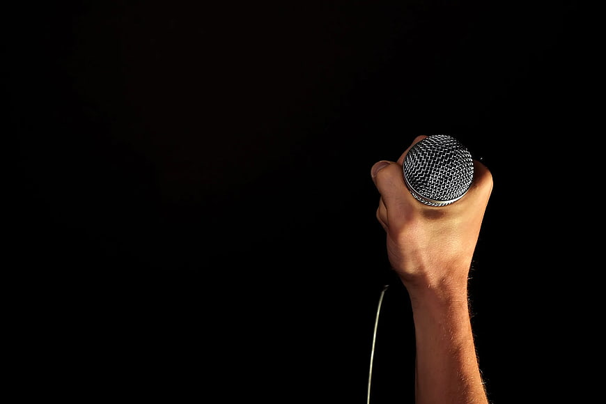 Hand Holding Microphone on Black Background