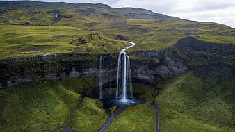 Aerial view of majestic waterfall cascading into lush green valley