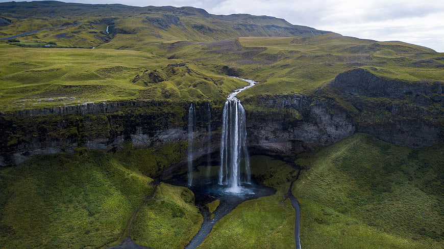Aerial view of majestic waterfall cascading into lush green valley