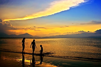 Family Silhouettes Walking on Beach at Golden Sunset