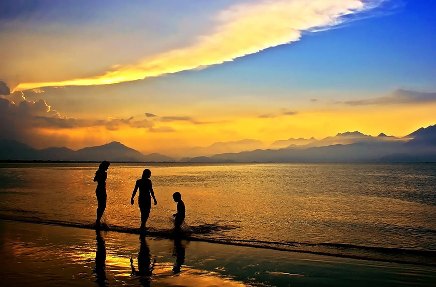 Family Silhouettes Walking on Beach at Golden Sunset