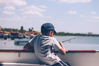 Young boy fishing from a boat on a sunny day