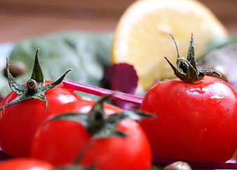 Close-up of fresh red tomatoes with lemon and salad ingredients