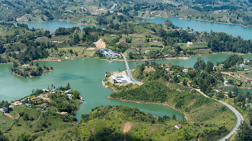 Aerial view of winding lake surrounded by green hills and houses