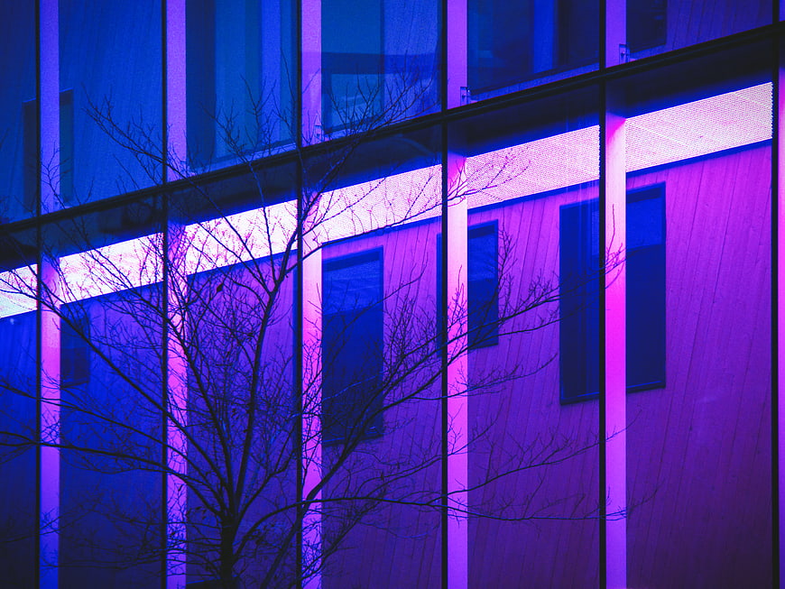 Modern Glass Building Facade with Neon Blue and Purple Lighting