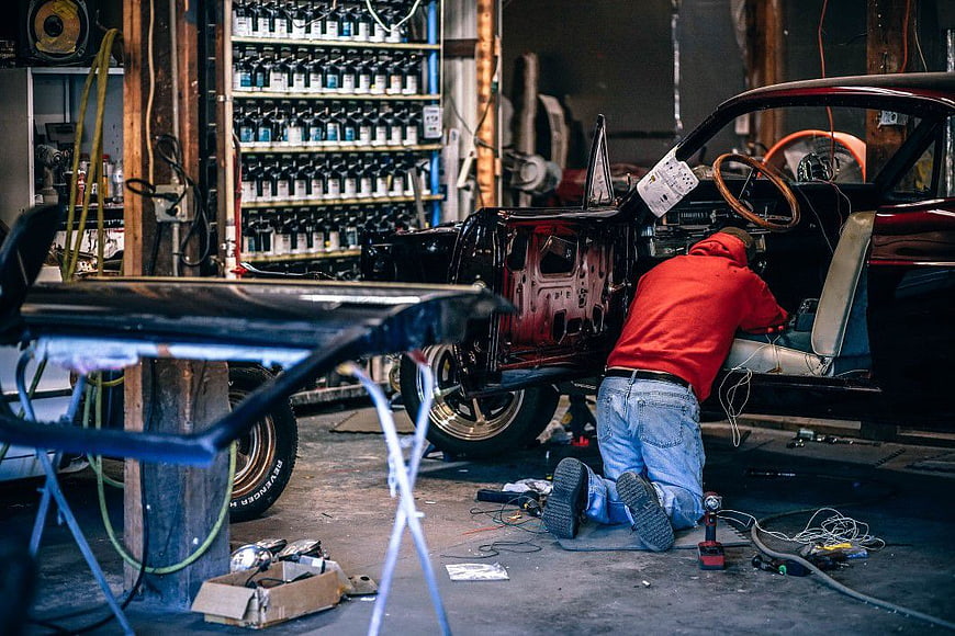 Mechanic working on classic car restoration in garage