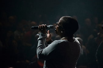 Woman singing into microphone on dark stage
