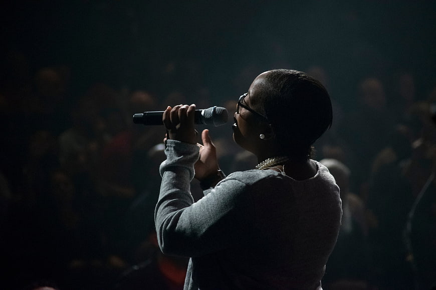 Woman singing into microphone on dark stage