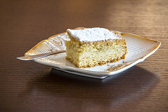 Slice of cream cake with powdered sugar on vintage plate