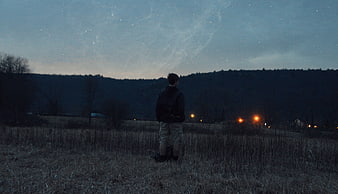 Young Man Standing in Field Under Starry Night Sky