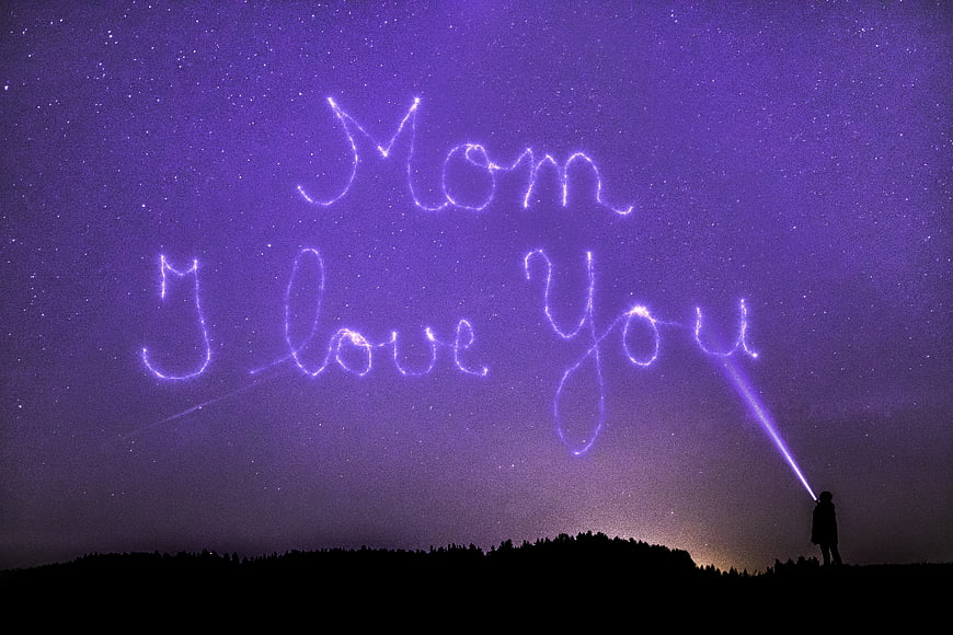 Person Writing Mom I Love You in Stars with Flashlight