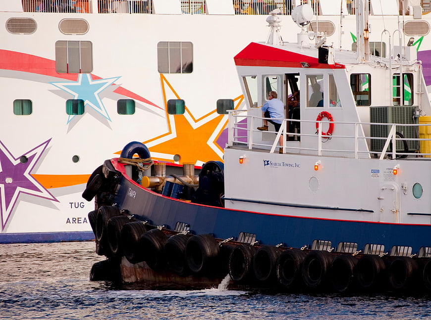Tugboat Tampa assisting large cruise ship in port