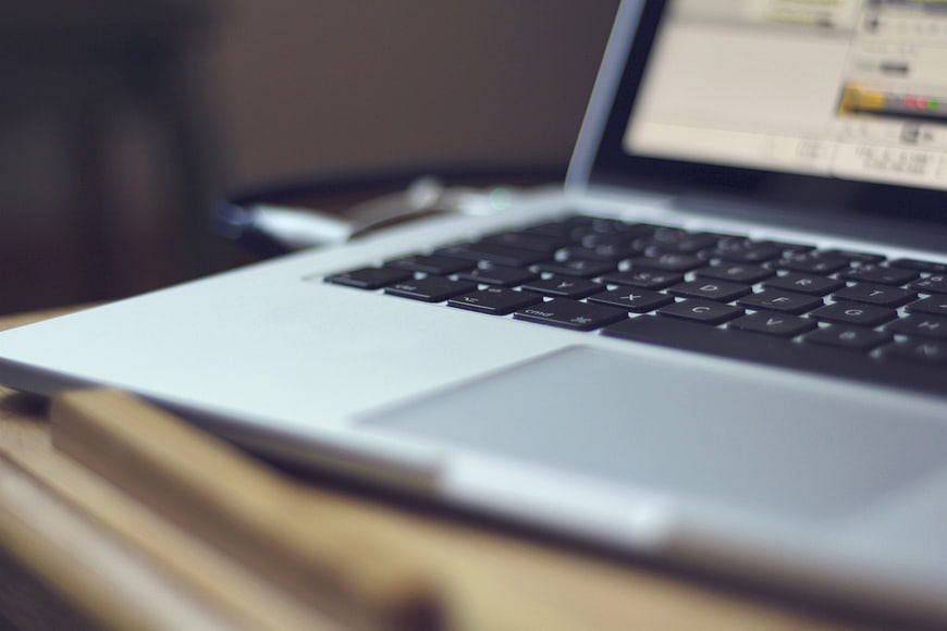 Close-up of silver laptop keyboard on wooden desk