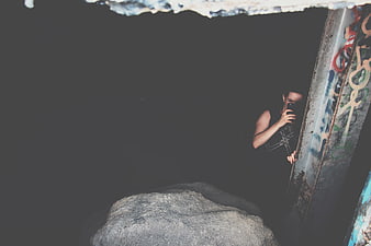 Woman taking selfie in dark urban setting with graffiti
