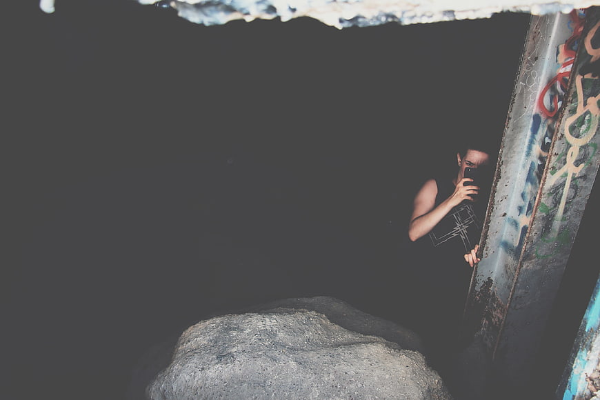 Woman taking selfie in dark urban setting with graffiti