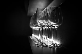 Black and white row of empty wine glasses in dramatic lighting