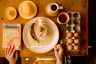 Flat lay breakfast with banana, eggs, coffee, and Breakfast of Champions book
