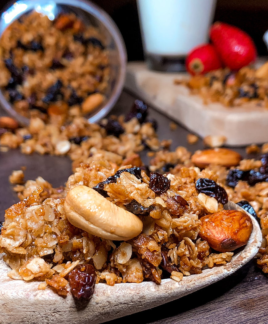 Close-up of crunchy granola with nuts and raisins on wooden spoon