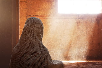 Woman in Knitted Hood Wrapped in Blanket by Sunlit Window