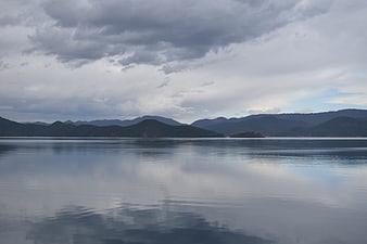 Serene Lake Landscape with Cloudy Sky and Mountain Reflections