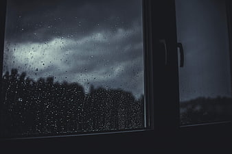 Raindrops on Window Glass Against Dark Stormy Sky
