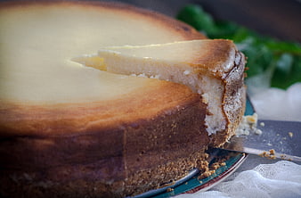 Close-up of a creamy cheesecake with a slice being served on a plate
