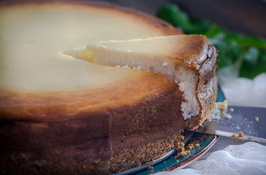 Close-up of a creamy cheesecake with a slice being served on a plate
