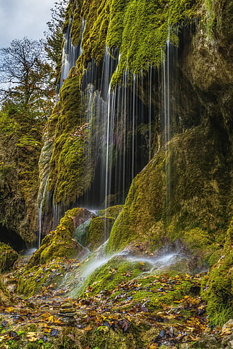 Mossy waterfall cascading down a rocky cliff in autumn