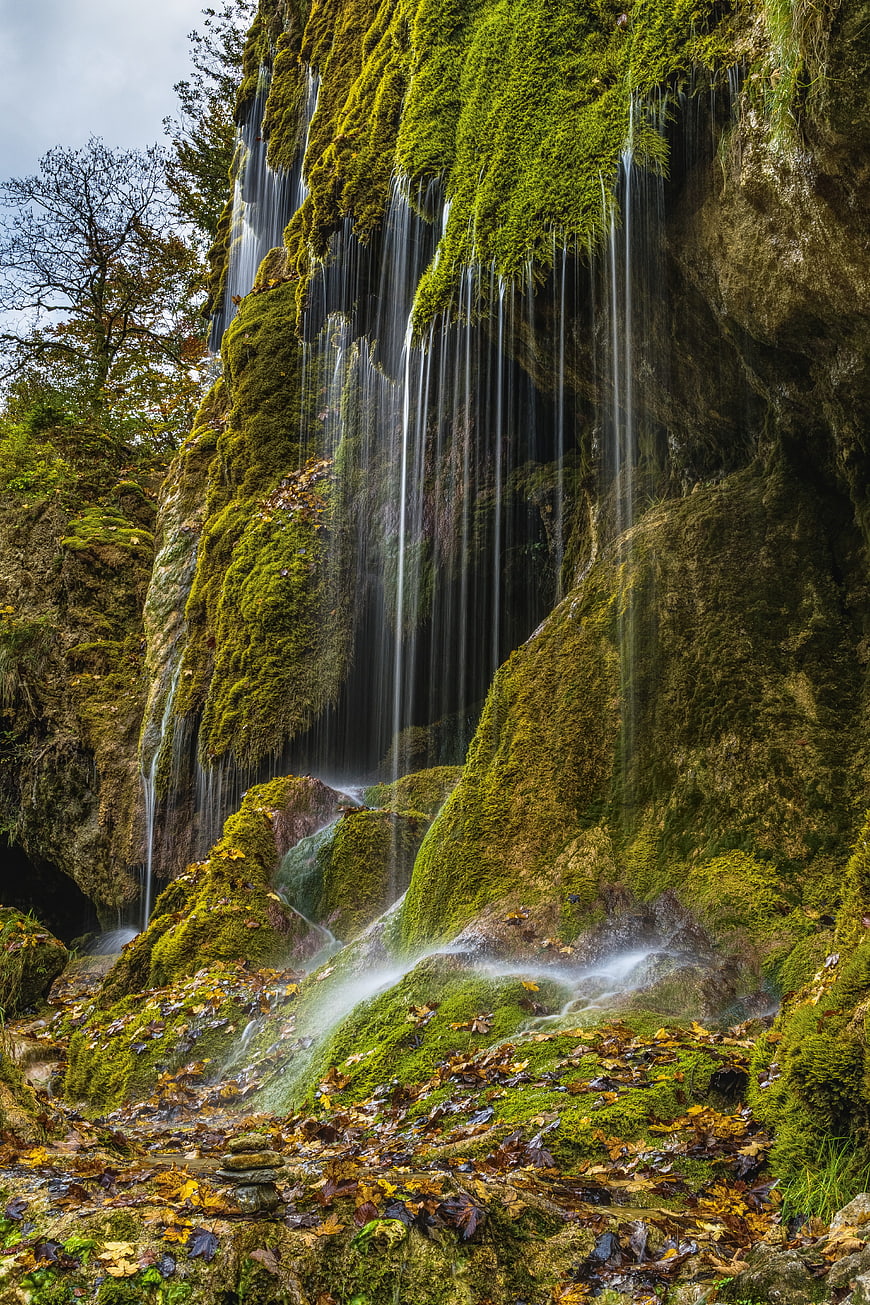 Mossy waterfall cascading down a rocky cliff in autumn