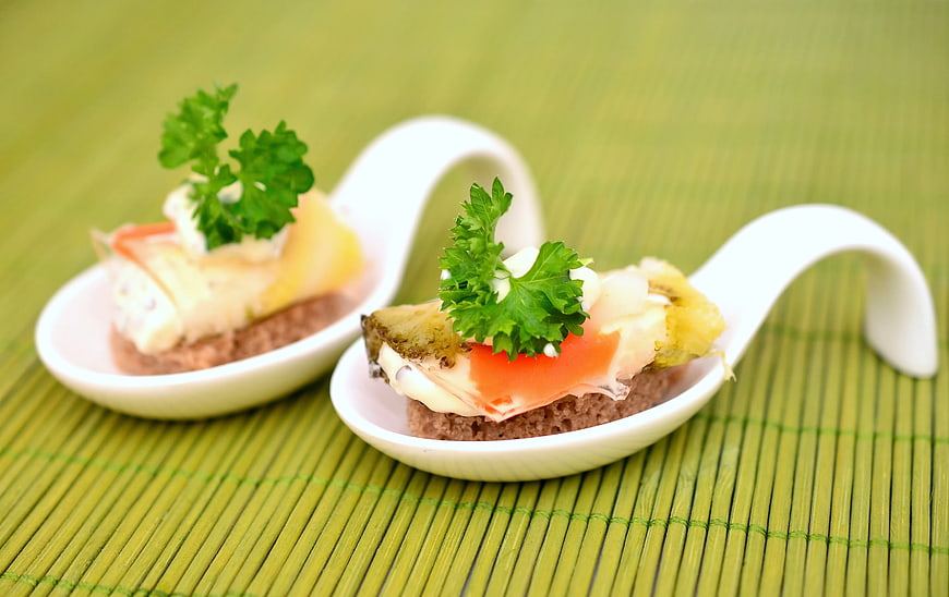 Gourmet Canapés on White Ceramic Spoons with Green Garnish