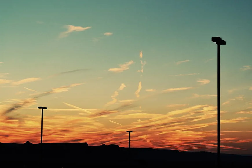 Silhouetted street lamps against a vibrant sunset sky