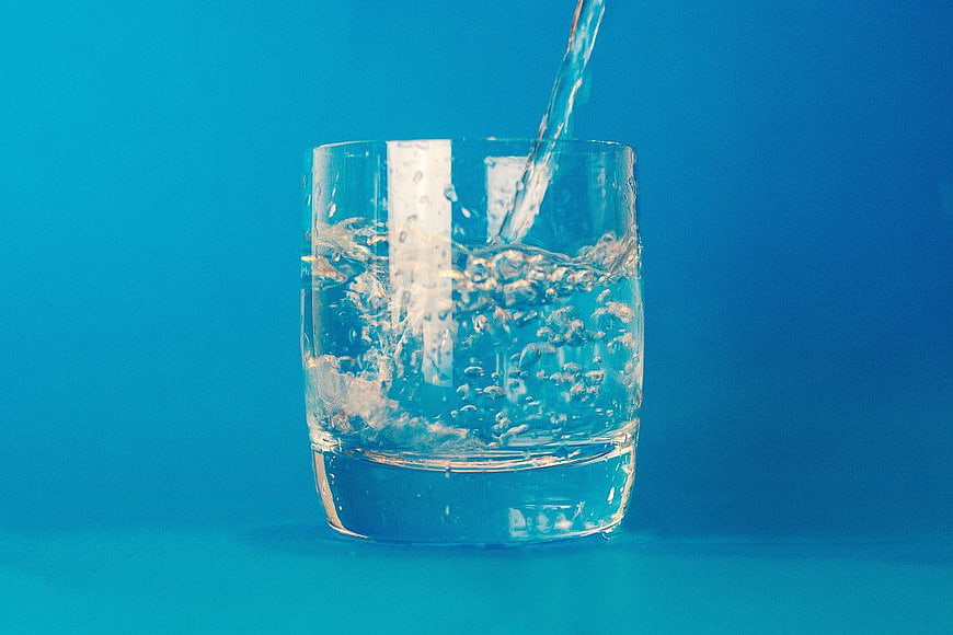 Water Pouring into Glass on Blue Background