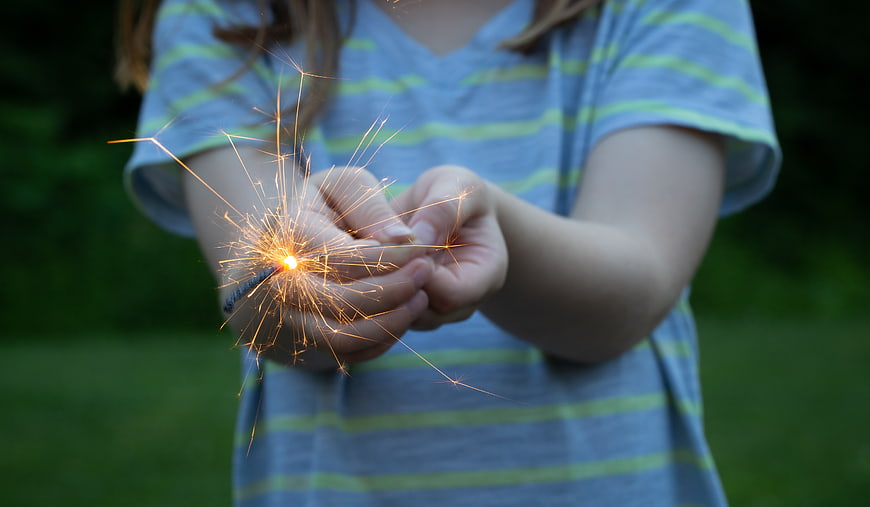 Child Holding Sparkler Outdoors at Dusk