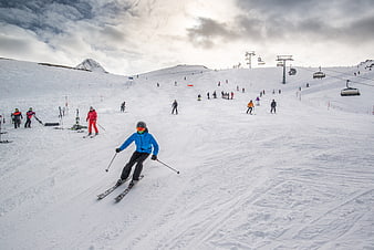 Skier in Blue Jacket Descending Snowy Mountain Slope