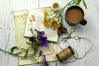 Vintage botanical book with flowers and coffee on rustic table