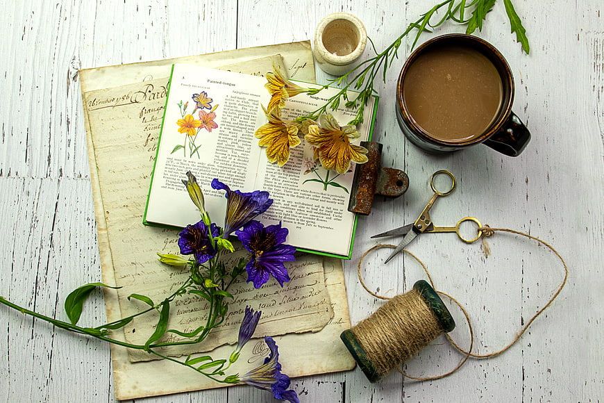 Vintage botanical book with flowers and coffee on rustic table