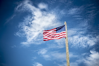 American Flag Flying Against Blue Sky With White Clouds