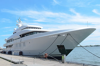 Luxury white yacht docked at marina on sunny day