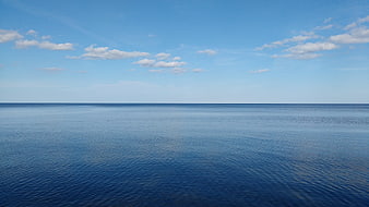 Serene Blue Ocean Horizon with Scattered White Clouds