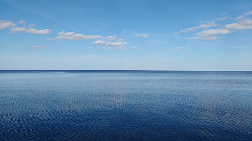 Serene Blue Ocean Horizon with Scattered White Clouds
