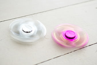 Two Spinning Fidget Spinners on White Wooden Surface