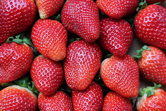 Close-up of fresh red strawberries with seeds and green leaves