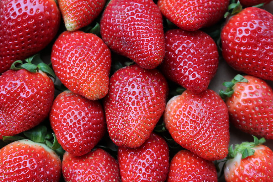 Close-up of fresh red strawberries with seeds and green leaves