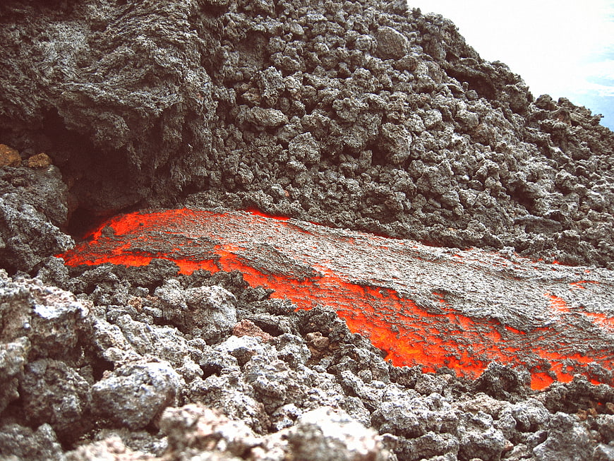Glowing red lava flowing through black volcanic rock