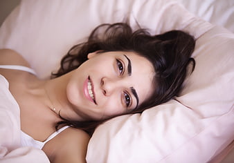 Happy young woman smiling while lying in bed