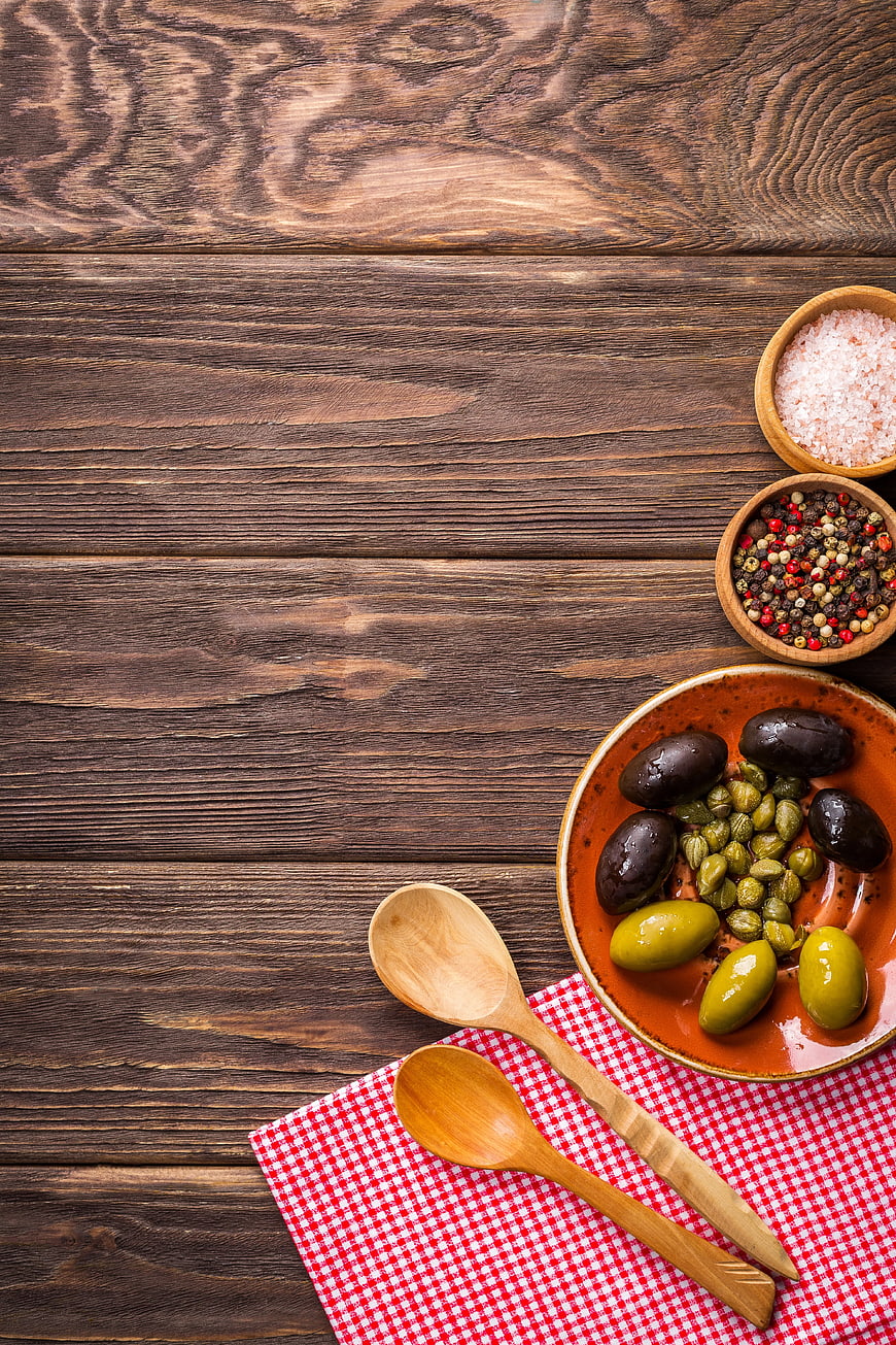 Top View of Olives, Capers, and Spices on Rustic Wood