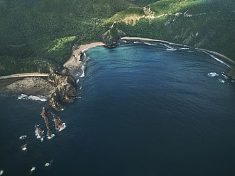 Aerial view of secluded tropical bay with turquoise water and lush cliffs