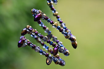 Colorful Faceted Beads Hanging Against Green Background